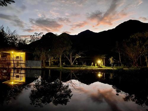 a sunset over a pond with mountains in the background at Numpu Baandin in Sam Roi Yot