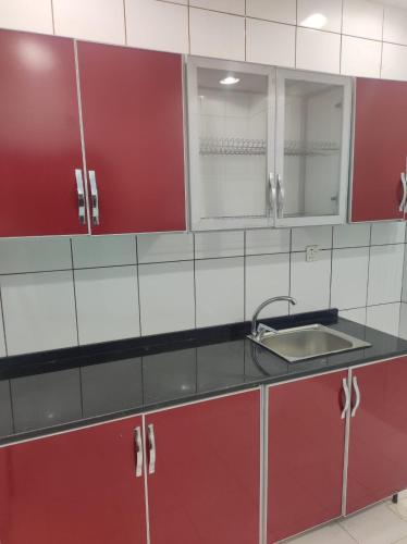 a kitchen with red and white cabinets and a sink at الياسمين للشقق المفروشة in Jeddah