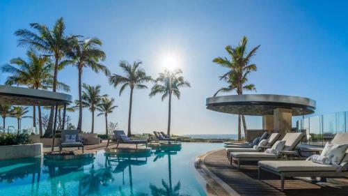 a pool at a resort with chairs and palm trees at Jewel Broadbeach Luxury Apartment - CoastHM in Gold Coast