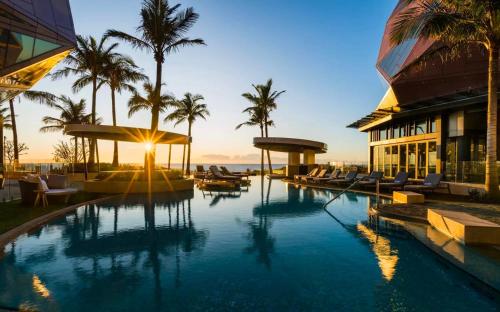 a resort pool with palm trees and a building at Jewel Broadbeach Luxury Apartment - CoastHM in Gold Coast