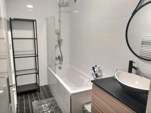 La salle de bains est pourvue d'un lavabo, d'une baignoire et d'un miroir. dans l'établissement Ch privée 23m - Canapé lit - WIFI - Appart 120m, à Woippy