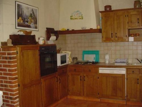 una cucina con armadi in legno e forno a microonde di Maison troglodytique avec WiFi, barbecue et cheminée - FR-1-410-156 a Aubigné-Racan