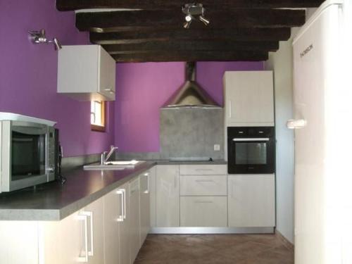 a kitchen with white cabinets and a purple wall at Gîte Saint-Mars-d'Outillé, 4 pièces, 8 personnes - FR-1-410-210 in Saint-Mars-dʼOutillé