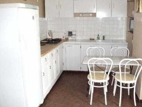 une cuisine avec des armoires blanches et une table et des chaises dans l'établissement Charmante longère avec grand terrain au bord de la forêt de Bercé, idéale pour des vacances paisibles - FR-1-410-200, à Saint-Vincent-du-Lorouër