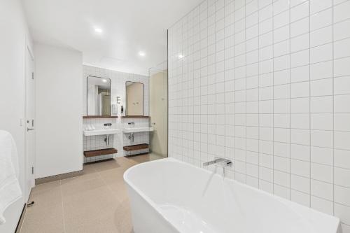 Baño blanco con bañera y 2 lavabos en Mercure Pakenham en Pakenham