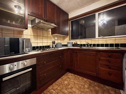 a large kitchen with wooden cabinets and a microwave at Vintage 3 Bedroom House near Catford in London