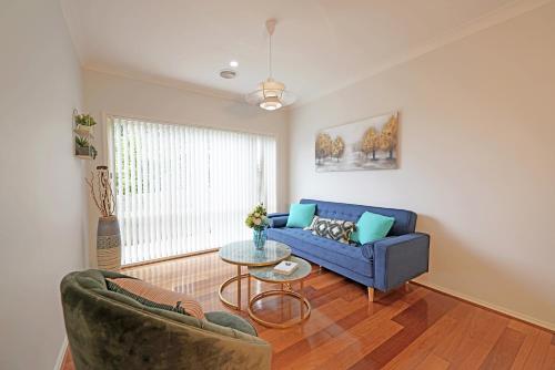 a living room with a blue couch and a table at Spacious 5BR House in Hallam near Bunjil Place in Hallam