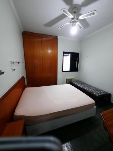 - une chambre avec un lit et un ventilateur de plafond dans l'établissement Apto no melhor ponto da Enseada, à Guarujá