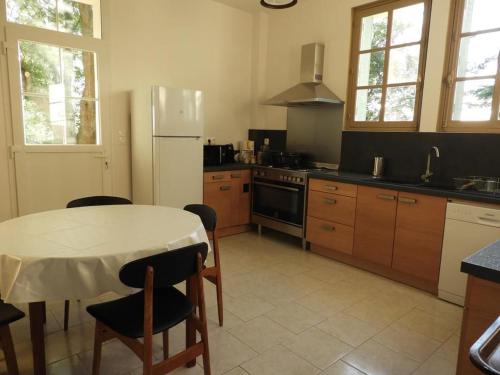 une cuisine avec une table et un réfrigérateur blanc dans l'établissement Gîte de charme au Mans, 4 chambres, grand jardin, terrasse, Wi-Fi, proche commerces - FR-1-410-318, à Écommoy