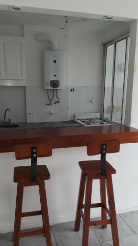 una cocina con 2 taburetes de madera en un mostrador en SANFER en San Fernando