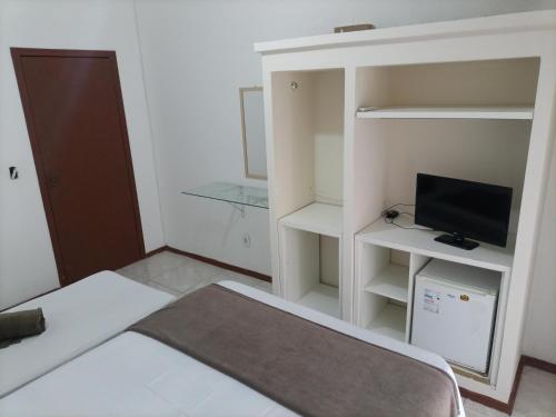 a small room with a bed and a television at Pousada Cama & Café in Navegantes