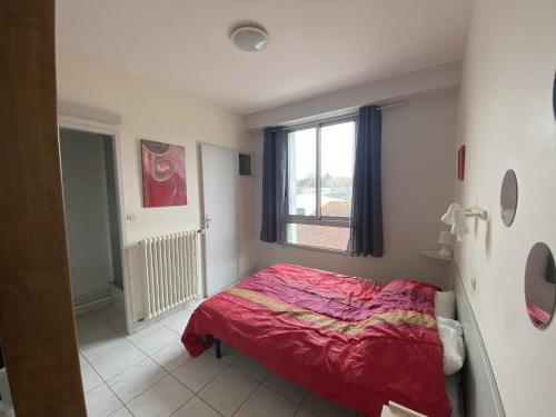 a bedroom with a red bed and a window at T2 Centre-ville La Roche-Posay, proche Thermes, Wi-Fi, laverie - FR-1-541-79 in La Roche-Posay