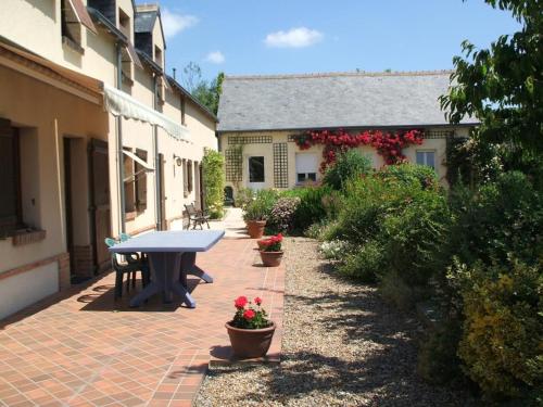 a patio with a picnic table and potted plants at Gîte spacieux avec billard, cheminée & terrasse, près de la forêt de Bercé, Wi-Fi & activités nature - FR-1-410-337 in Thoiré-sur-Dinan