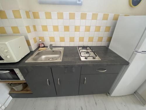 a small kitchen with a sink and a stove at Studio cosy en cœur de La Roche-Posay, proche Thermes, Wi-Fi, laverie, tout équipé - FR-1-541-84 in La Roche-Posay
