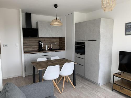 - une cuisine avec une table en bois et des chaises blanches dans l'établissement Appartement T2 Centre Ville avec Parking - Fort-Mahon-Plage - FR-1-482-94, à Fort-Mahon-Plage