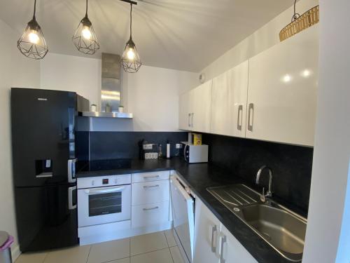 une cuisine avec des armoires blanches et un évier dans l'établissement Charmant T2 pour 4 personnes au cœur d'Arcachon avec WiFi et équipements modernes - FR-1-474-176, à Arcachon