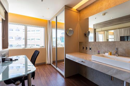 a bathroom with a sink and a desk and a mirror at You Stay at Vila Olimpia - ITC in Sao Paulo