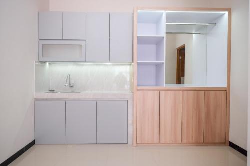 a kitchen with white cabinets and a sink and a mirror at RedDoorz Syariah near Solo Paragon Mall 2 in Bonorejo