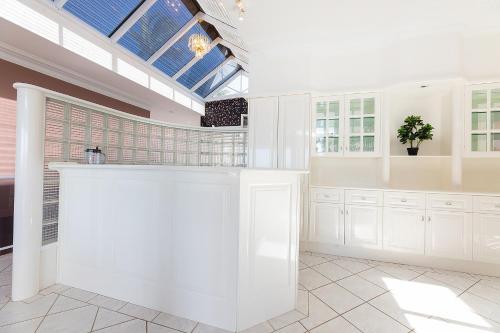 a large kitchen with white cabinets and a skylight at The Pink Palace in Forster