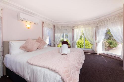 un dormitorio con una gran cama blanca con un perro sentado en ella en The Pink Palace, en Forster