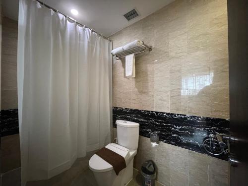 a bathroom with a toilet and a shower curtain at Travellers Hotel Phinisi in Makassar