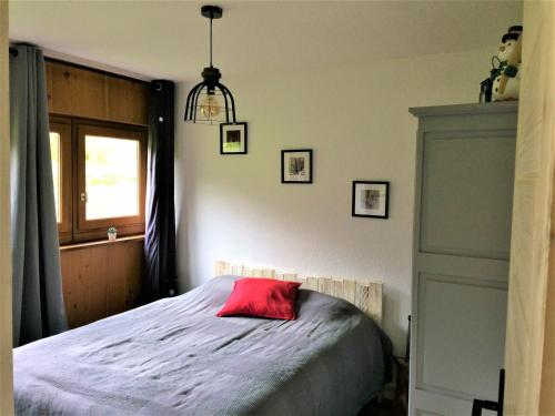 ein Schlafzimmer mit einem Bett mit einem roten Kissen darauf in der Unterkunft Appartement Mont-Dore, 2 pièces, 5 personnes - FR-1-415-114 in Le Mont-Dore