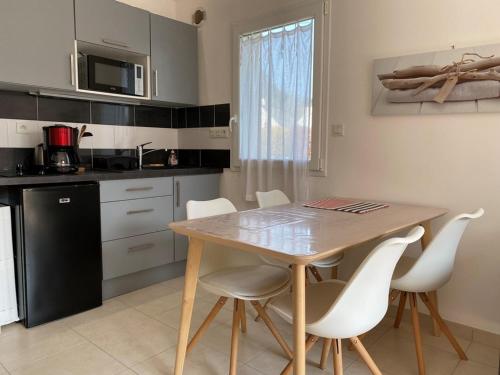 - une cuisine avec une table en bois et des chaises blanches dans l'établissement Maison 3 pièces avec jardin, Terrasse, Wifi - Proche plages et sentiers côtiers - Erdeven - FR-1-397-55, à Erdeven