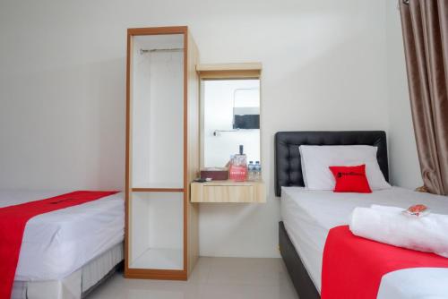 a bedroom with two beds and a mirror at RedDoorz Syariah near RS Hermina Yogyakarta in Seturan