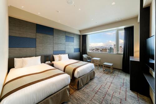 a hotel room with two beds and a large window at HOTEL VISCHIO TOYAMA in Toyama