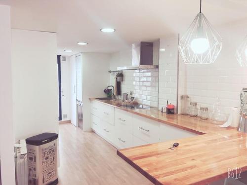 a kitchen with white cabinets and a wooden counter top at Adosado, wifi, playa, lugar espacioso, vacacional in Grao de Castellón