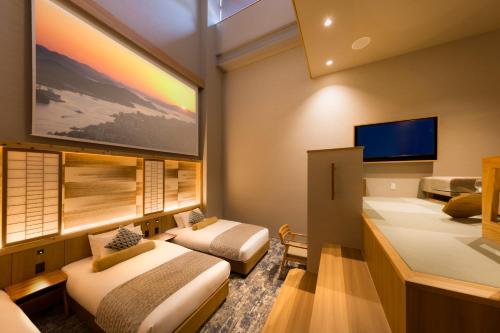 um quarto de hotel com duas camas e uma televisão de ecrã plano em HOTEL BEACON ONOMICHI em Onomichi