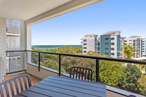 a balcony with a blue table and chairs and the ocean at San Marino by the Sea Apartments in Marcoola