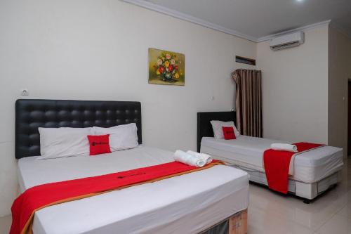 1 dormitorio con 2 camas con sábanas rojas y blancas en RedDoorz Syariah near RS Hermina Yogyakarta, en Seturan