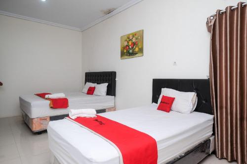 two beds in a room with red and white sheets at RedDoorz Syariah near RS Hermina Yogyakarta in Seturan
