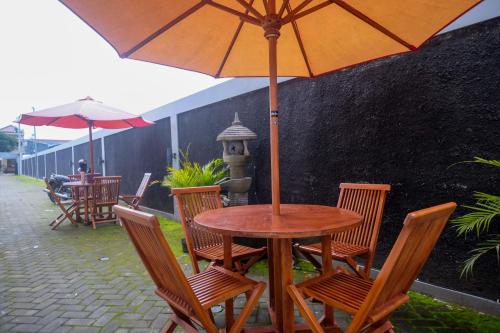 a wooden table with chairs and an umbrella on a patio at RedDoorz Syariah near RS Hermina Yogyakarta in Seturan