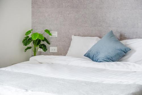 a white bed with a blue pillow and a plant at Penghu SunSea Hall in Magong