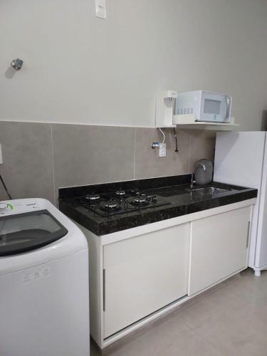 a kitchen with a stove and a microwave at FLAT SABIÁ in Uberlândia