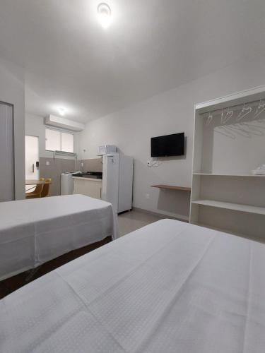 a white room with two beds and a tv at FLAT SABIÁ in Uberlândia