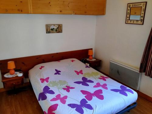 Un dormitorio con una cama con mariposas moradas. en Appartement Mont-Dore, 2 pièces, 5 personnes - FR-1-415-113, en Le Mont-Dore