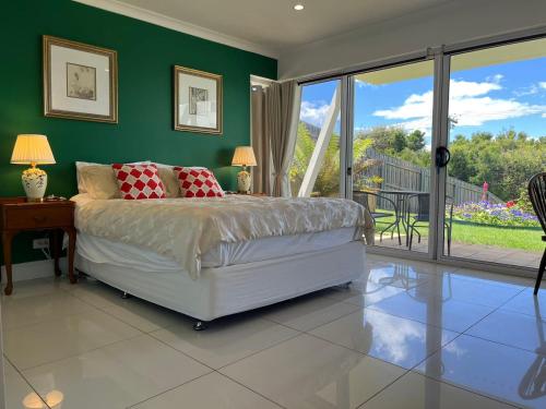a bedroom with a bed and green walls and a balcony at White House in Bicheno