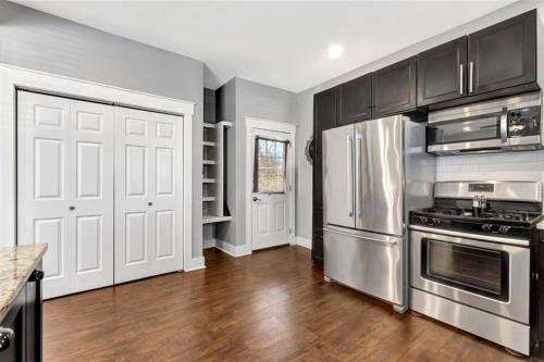 a kitchen with stainless steel appliances and wooden floors at Vibrant Vacation Escape with Fast WIFI and KING BED Close to Downtown Houston! in Houston