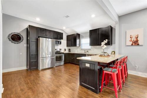 a kitchen with a refrigerator and a table with red stools at Vibrant Vacation Escape with Fast WIFI and KING BED Close to Downtown Houston! in Houston