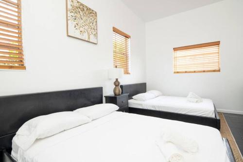 twee bedden in een kamer met witte muren en ramen bij Modern 5 Bedroom Miami Home 15 Min to the Beach in Miami