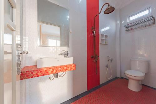 y baño con aseo blanco y lavamanos. en Urbanview Palace Syariah Balikpapan by RedDoorz, en Balikpapan