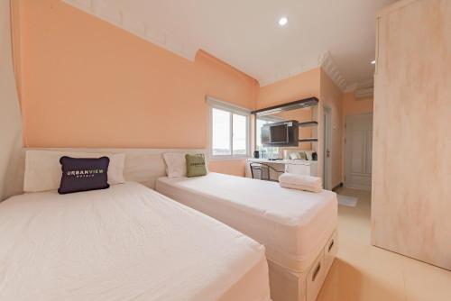 Habitación pequeña con 2 camas y TV. en Urbanview Palace Syariah Balikpapan by RedDoorz, en Balikpapan