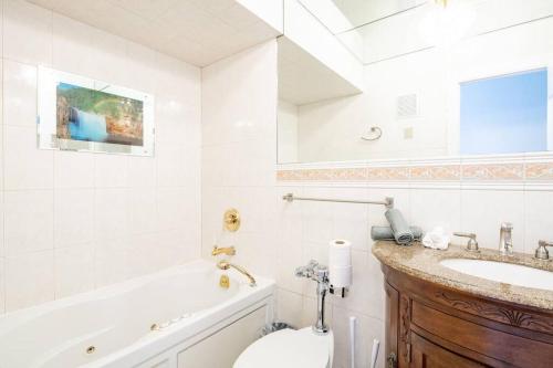 a bathroom with a sink and a toilet and a tub at Waterfront 2-Story Villa with Heated Pool in Pembroke Pines