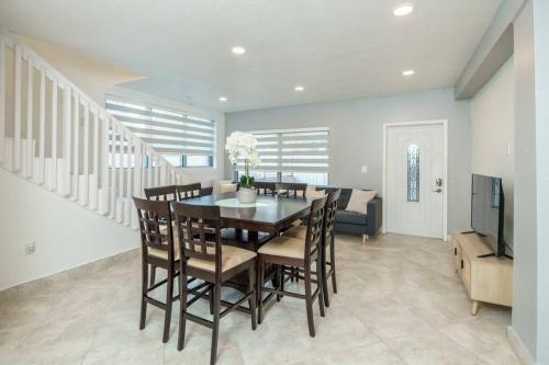 a dining room with a table and chairs and a television at Beautiful 7-Bedroom Villa with Pool in Hialeah