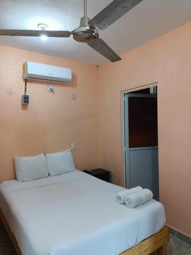 a bedroom with a white bed and a fan at Casa Bonzay in Bacalar