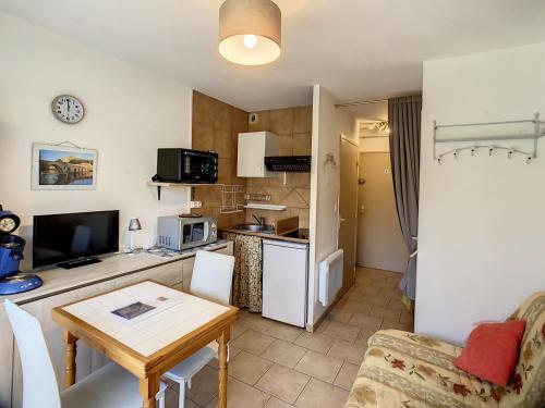 un salon avec une table et une cuisine dans l'établissement Charmant T1 au cœur de Lamalou, à 650m des Thermes, avec Wifi et animaux acceptés - FR-1-451-147, à Lamalou-les-Bains