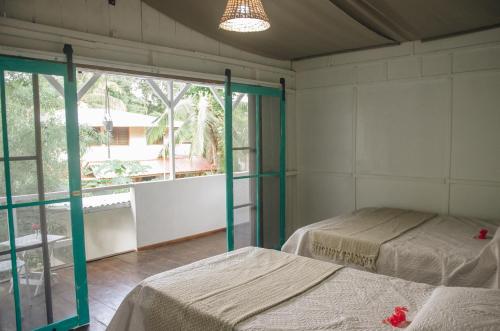 a bedroom with two beds and a large window at Casa BOHÖ in Puerto Viejo
